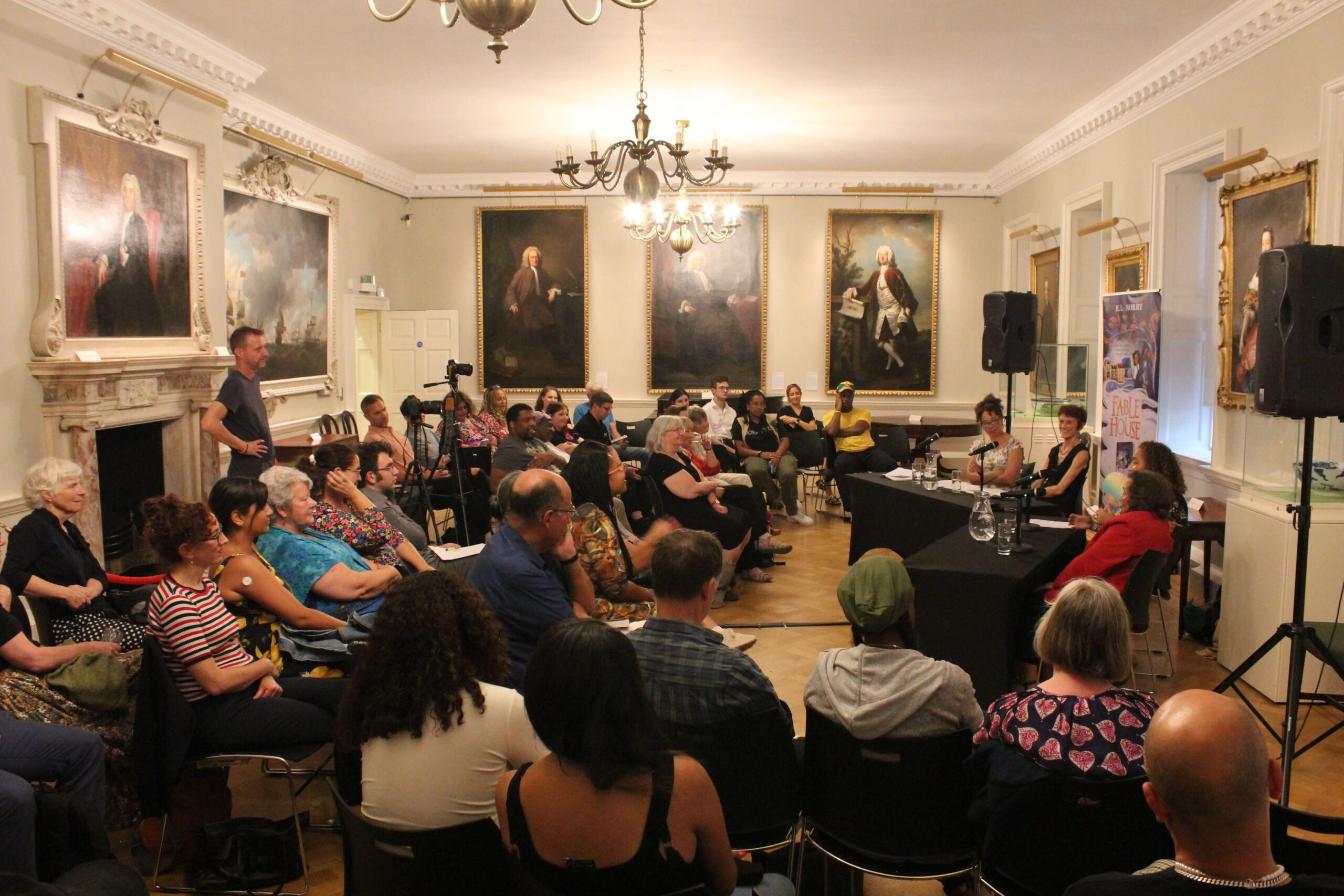 A panel discussion in a packed ornate room