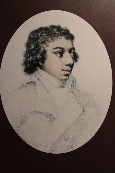 Side profile portrait of a mixed race man with short wavy hair. He is wering a cravat and jacket and looking into the distance with a faint smile.