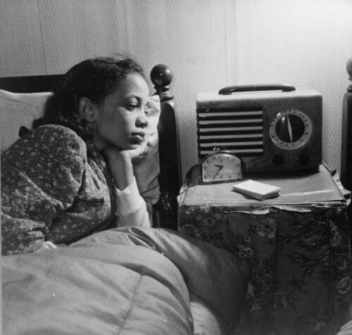 Black and white photo of an African American woman listening to the wireless radio