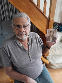 Photograph of Bill Wiley at home hold ing a picture of his African American GI father.