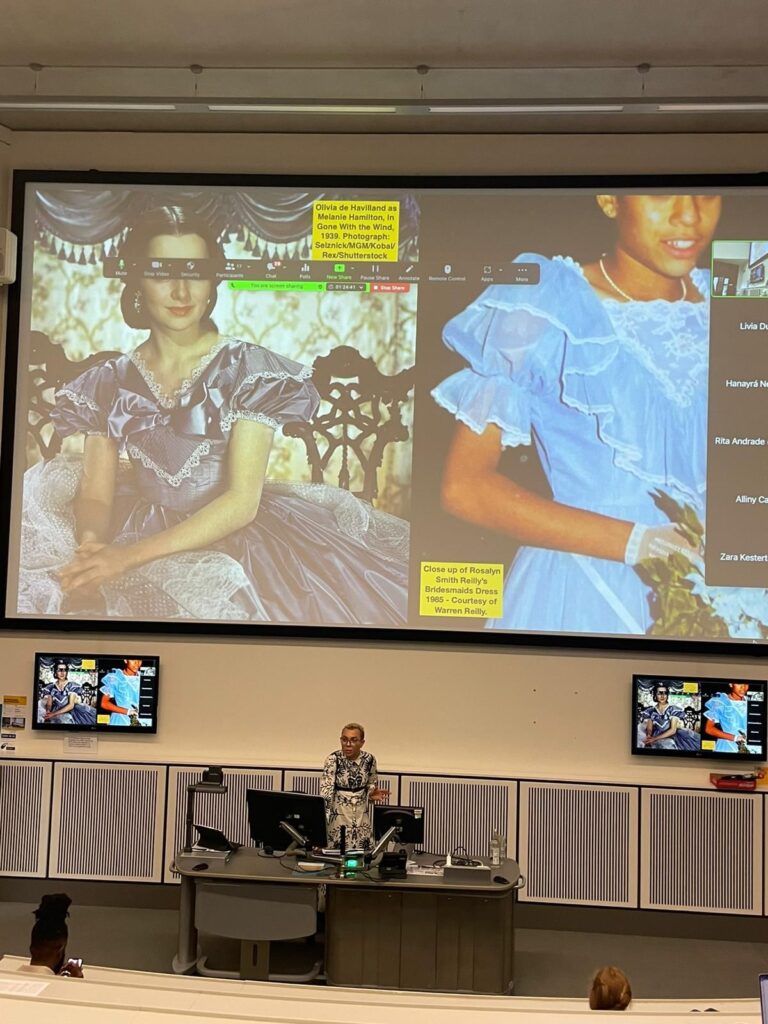 Warren Reilly standing in front of a presentation comparing a mixed race woman in a 1980s' bridesmaid's dress to Scarlett O'Hara's dress in Gone With the Wind.