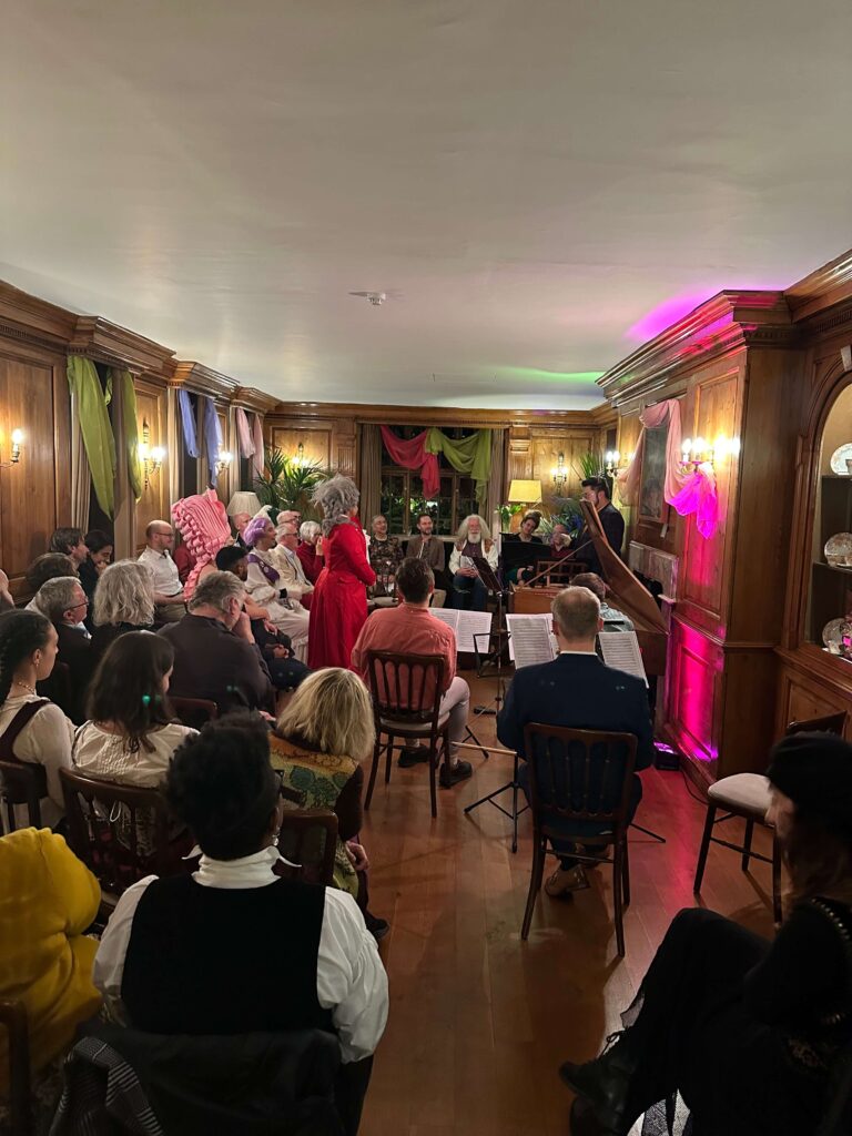 A group of people in a Georgian style room listening to an intimate classical music concert.