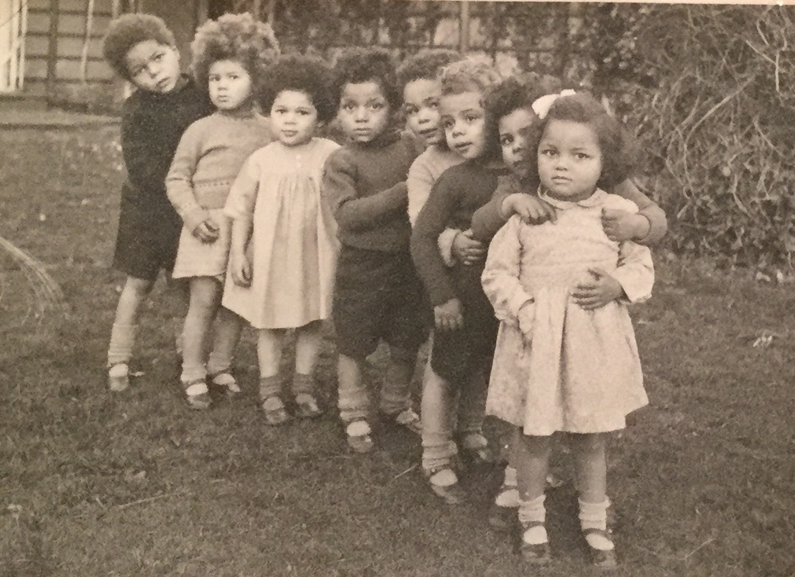 A photograph of some of Britain's 'Brown Babies' of WW2, standing in a line and looking at the camerar.